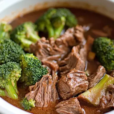 Close-up of crockpot beef and broccoli in a slow cooker, with tender shredded beef and vibrant green broccoli in a rich brown garlic sauce.
