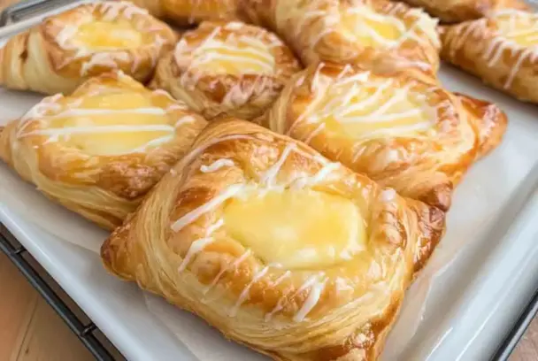 Tray of golden brown Cheese Danishes with flaky puff pastry, cream cheese filling, and vanilla glaze, cooling on a wire rack.