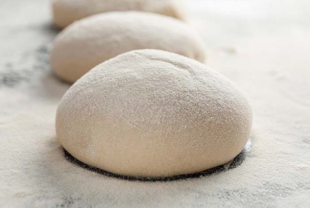 Homemade pizza dough rolled out on a floured surface, ready for toppings and baking