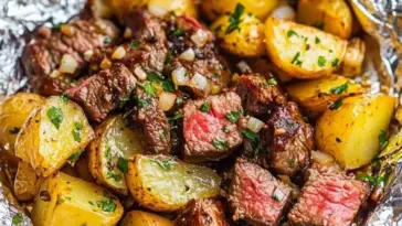 Juicy steak cubes and golden roasted potatoes seasoned with herbs and garlic, served hot in a foil packet for an easy and flavorful meal.