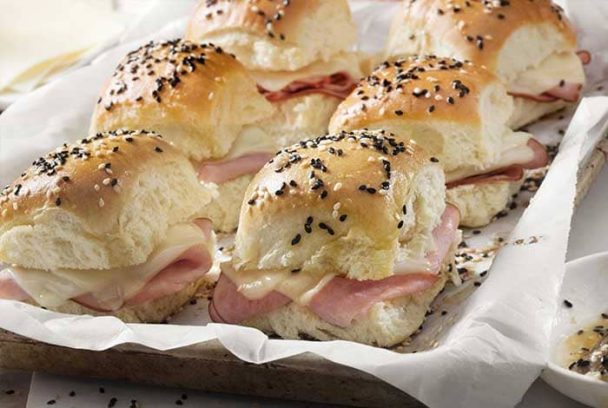 Ham and cheese sliders baked on Hawaiian rolls with a buttery glaze on top, served warm from the oven