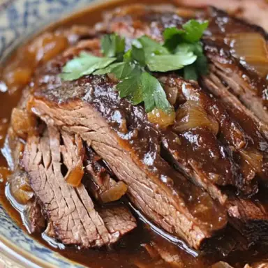 Sliced slow-cooked beef brisket topped with fresh parsley and served in a flavorful onion gravy in a decorative bowl.