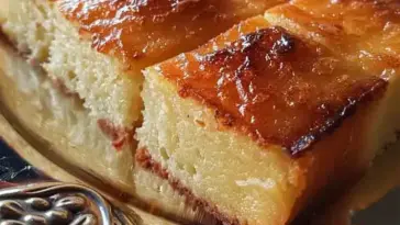 Sliced Turkish Milk Cake with a golden, glossy top and soft, creamy interior, served on a decorative silver tray.