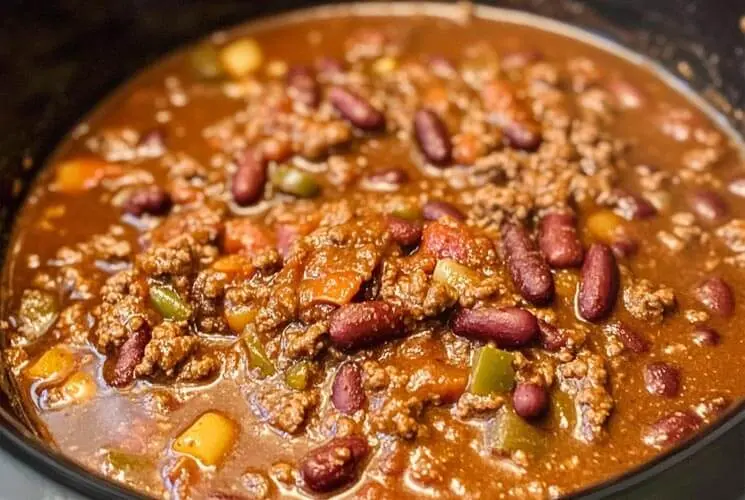 Close-up of crockpot chili with ground beef, kidney beans, tomatoes, and green bell peppers in a thick, savory sauce, ready to serve.