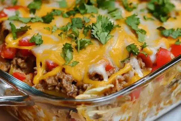 Cheesy Mexican white trash casserole made with ground beef, black beans, corn, creamy sauce, and crunchy tortilla chips, baked until golden and bubbly.