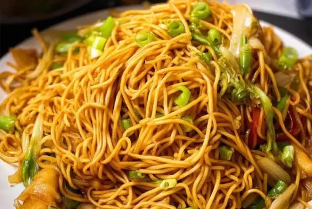 A heaping plate of homemade Panda Express-style chow mein with golden noodles, cabbage, celery, and green onions