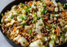 Skillet filled with Chinese ground beef and cabbage stir fry featuring green onions, carrots, and stir-fried cabbage in a savory soy-based sauce.