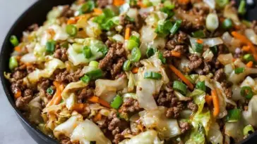 Skillet filled with Chinese ground beef and cabbage stir fry featuring green onions, carrots, and stir-fried cabbage in a savory soy-based sauce.