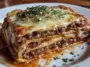 Slice of Italian lasagna with visible layers of meat sauce, pasta, and melted cheese, topped with parsley and served on a white plate.