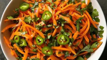 Top view of a vibrant shredded carrot and serrano chile salad with chopped cilantro, served in a white bowl — colorful, spicy, and fresh.