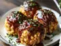 Close-up of four golden mac and cheese bombs filled with pulled pork and topped with maple bourbon BBQ sauce, garnished with fresh herbs on a white plate.