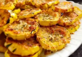 Plate of golden-brown baked Parmesan squash slices with a crispy cheese coating, arranged neatly on a white serving dish.