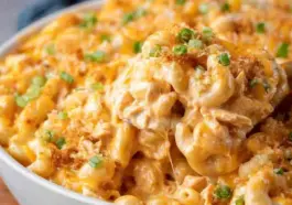 Bowl of baked Buffalo Chicken Mac and Cheese topped with golden breadcrumbs and chopped green onions, featuring creamy sauce and melted cheese.