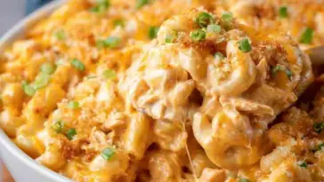 Bowl of baked Buffalo Chicken Mac and Cheese topped with golden breadcrumbs and chopped green onions, featuring creamy sauce and melted cheese.