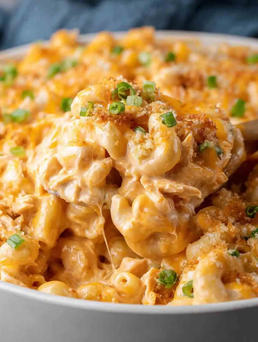 Close-up of creamy Buffalo Chicken Mac and Cheese topped with melted cheese, green onions, and crispy breadcrumbs in a white bowl.