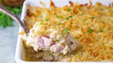Spoonful of Chicken Cordon Bleu Casserole with creamy sauce, diced ham, and crispy golden breadcrumb topping in a white baking dish.