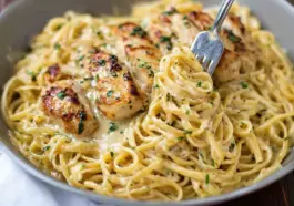A close-up of creamy Garlic Parmesan Chicken Pasta in a bowl, with golden seared chicken slices on top of linguine tossed in a rich garlic parmesan sauce, garnished with chopped parsley and a fork twirling the noodles.