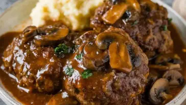 Juicy beef Salisbury steaks topped with mushroom-onion gravy, served with creamy mashed potatoes on a plate—classic comfort food made in the Instant Pot.