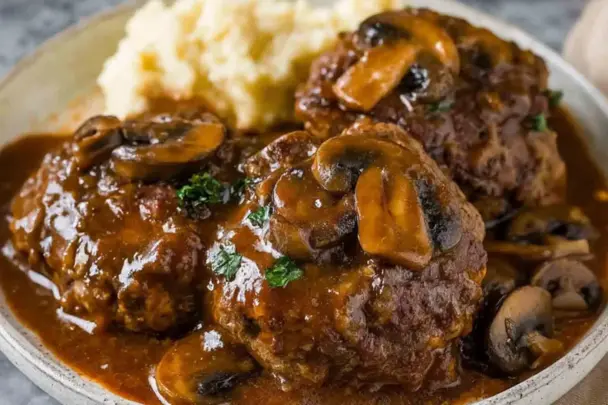 Juicy beef Salisbury steaks topped with mushroom-onion gravy, served with creamy mashed potatoes on a plate—classic comfort food made in the Instant Pot.
