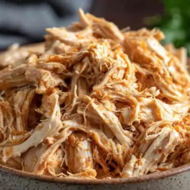 A bowl filled with juicy, tender Instant Pot shredded chicken, perfectly seasoned and ready to use in wraps, salads, tacos, or meal prep dishes.