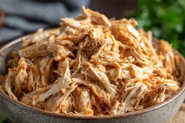 A bowl filled with juicy, tender Instant Pot shredded chicken, perfectly seasoned and ready to use in wraps, salads, tacos, or meal prep dishes.