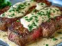 Two thick, pan-seared steaks topped with creamy garlic sauce and garnished with fresh parsley, served on a plate with sauce pooled around the meat.