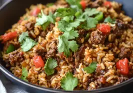 Close-up of one-skillet smoky honey chili beef rice topped with fresh cilantro and red bell peppers, served in a black bowl.