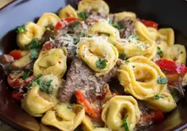 Close-up of Philly Cheesesteak Tortellini in a bowl, with creamy cheese sauce, sautéed red peppers, onions, mushrooms, and tender steak slices