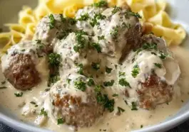 Close-up of creamy Swedish meatballs garnished with fresh parsley, served over egg noodles with rich white gravy, all made in a slow cooker.