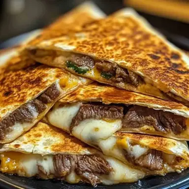 A stack of golden, crispy steak cheese quesadillas filled with juicy beef and melted cheese, served on a dark plate for a comforting and satisfying meal.