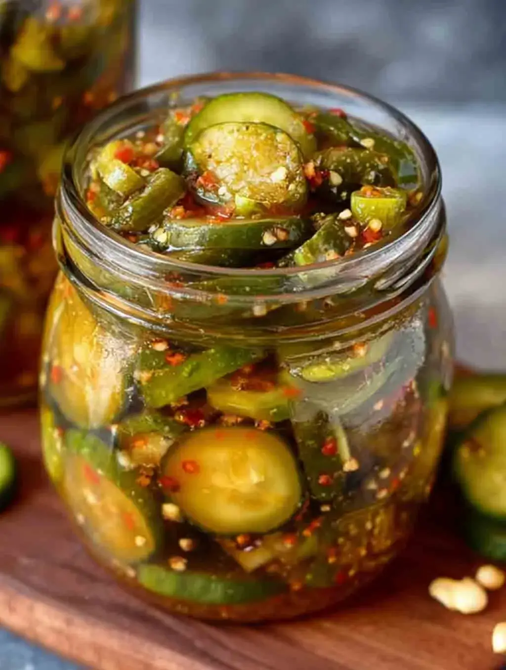 A close-up of a mason jar filled with homemade Sweet Heat Pickles, featuring sliced cucumbers, red pepper flakes, and jalapeños in a vibrant spicy brine.