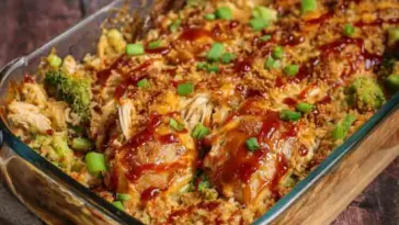 Glass baking dish filled with Teriyaki Chicken Casserole, showing shredded chicken, broccoli, rice, and a glossy teriyaki sauce, topped with chopped green onions.