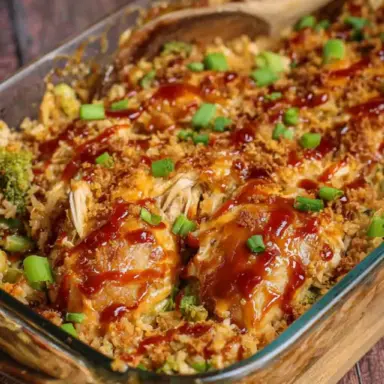 A baked Teriyaki Chicken Casserole in a glass dish, topped with a glossy teriyaki glaze, chopped green onions, and a golden crispy topping, served with a wooden spoon.