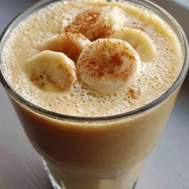 Glass of creamy banana smoothie topped with banana slices and cinnamon, ideal for a healthy weight loss breakfast.