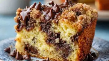 Moist slice of chocolate chip coffee cake with rich cinnamon streusel topping and melted chocolate chips, served on a patterned plate.