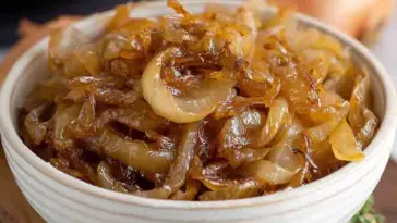 A bowl filled with tender, slow-cooked caramelized onions, glistening with sweet golden-brown color—perfectly cooked in the CrockPot.