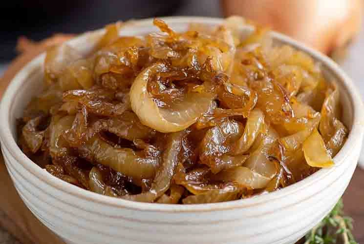A bowl filled with tender, slow-cooked caramelized onions, glistening with sweet golden-brown color—perfectly cooked in the CrockPot.