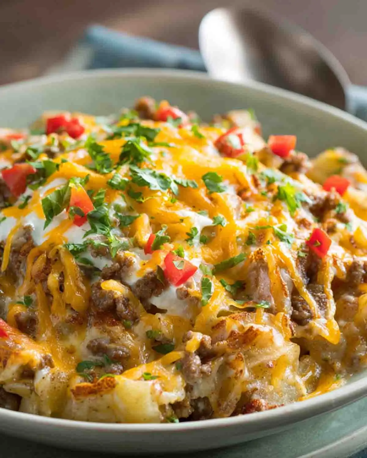 Close-up of slow cooker cowboy potato casserole with ground beef, melted cheddar cheese, diced potatoes, and fresh parsley garnish in a creamy sauce