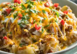 Slow cooker cowboy potato casserole with ground beef, melted cheddar cheese, diced potatoes, and fresh herbs in a creamy sauce