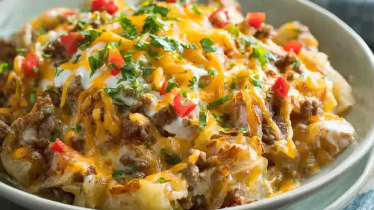 Slow cooker cowboy potato casserole with ground beef, melted cheddar cheese, diced potatoes, and fresh herbs in a creamy sauce